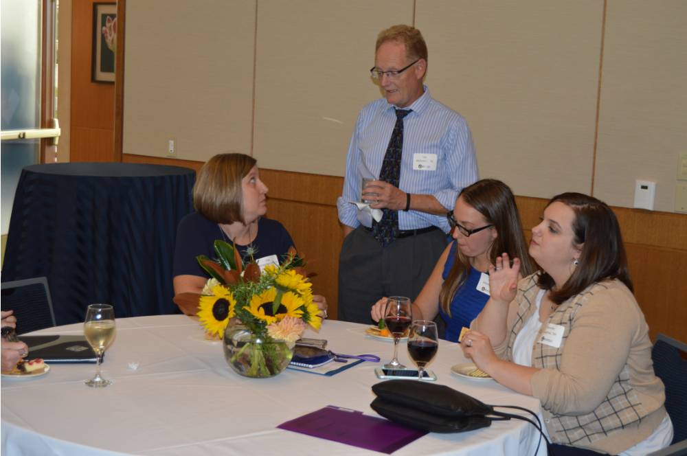 Four alumni enjoying conversation at the table